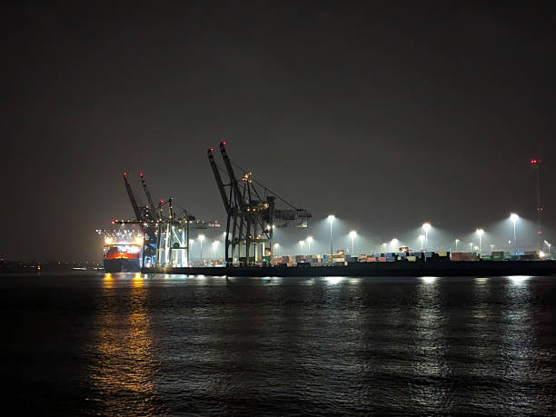 Hamburg, Germany - 26/08/2023: Gantry cranes and container ships at night in the harbor with lighting
