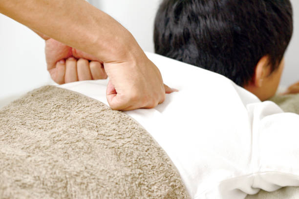 A young woman getting needles inserted into her back during an acupuncture session. A patient getting alternative therapy for medical treatment