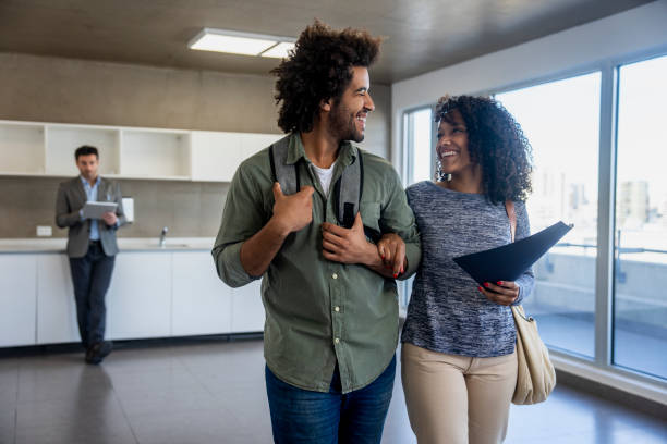 istock Couple visiting empty apartment for sale while real estate agent standing in background 2150134368