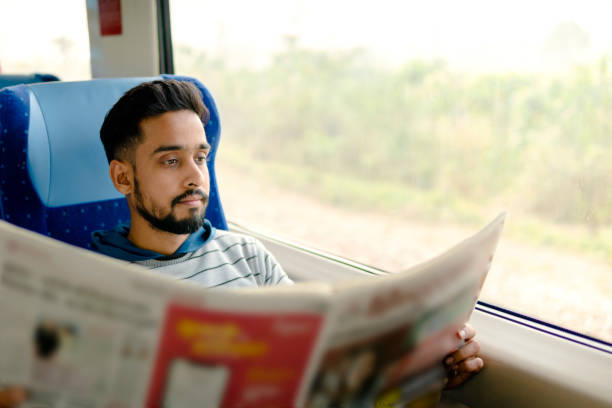 istock Young man reading a newspaper while traveling by the train. 2150134373