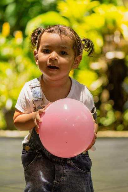 Little girl in joyful moments in her yard. Lots of fun and joy amidst lots of plants, flowers and nature.