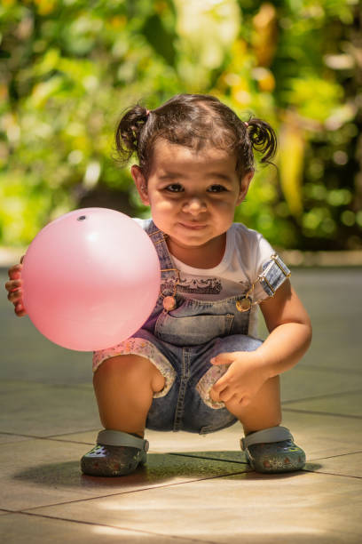 Cute baby playing with red gum ball. New born child, little girl having fun, grabbing and crawling. Family, new life, childhood, beginning concept. Baby learning grab