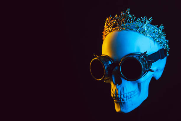 istock human skull in a crown and steampunk glasses with colored yellow blue neon light 2150135279