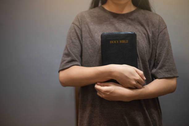 istock Woman standing and hugging a Bible. 2150136125