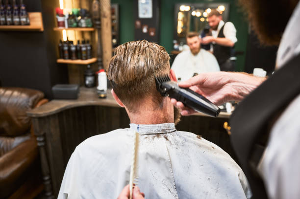 istock Professional barber using comb and electric shaver to cut side hair. 2150140924
