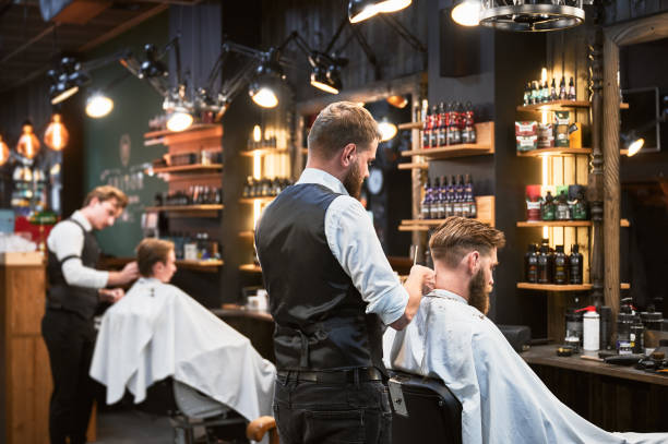 istock Professional barbers working on client hair in barbershop. 2150140929