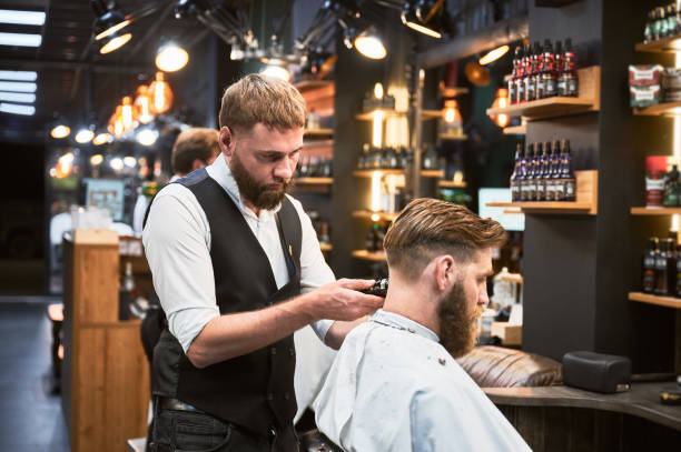 istock Professional barber using comb and electric shaver to cut side hair. 2150140938