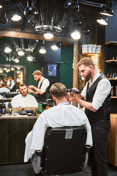 istock Professional barber using comb and electric shaver to cut side hair. 2150140940