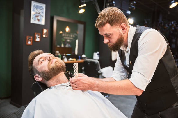 istock Close-up of professional barber trimming client's beard. 2150140941