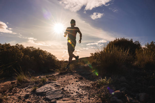 istock Runner silhouetted against the backdrop of a star shaped sun, navigating through a rugged trail amidst nature. 2150141760