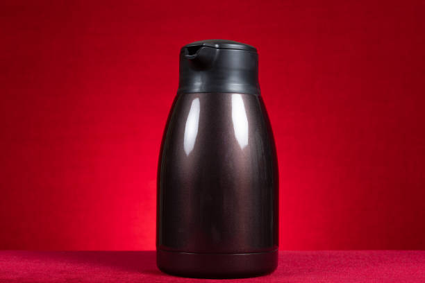 a stainless steel thermos bottle on red at horizontal composition