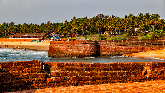 The Fort Aguada by the Sinquerim Beach, Sinquerium, Kandoli, Goa, India. The palm trees grow along the beautiful Indian ocean beach.