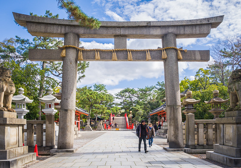 Torii gate and stone statues before the entrance to Sumiyoshi-taisha temple complex in Osaka, Japan.