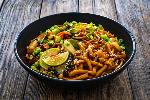 Asian style stir fried vegetables and noodles on wooden background
