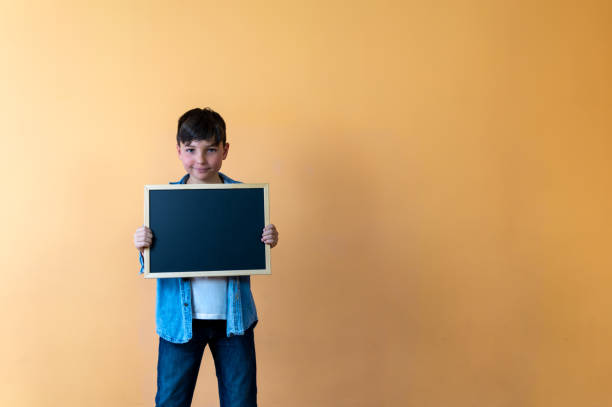 istock Smiling boy holding a blackboard for announcement 2150149739