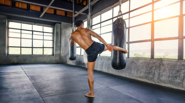 istock Muay thai fighter training in gym with punching bag 2150149841
