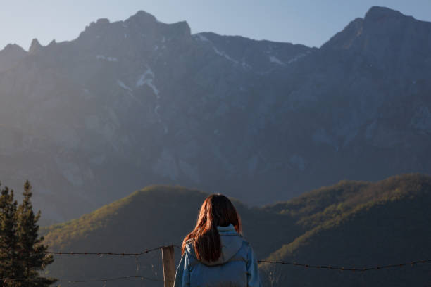 istock Rear view of blurred woman admiring mountains at sunset. Copyspace. 2150149877