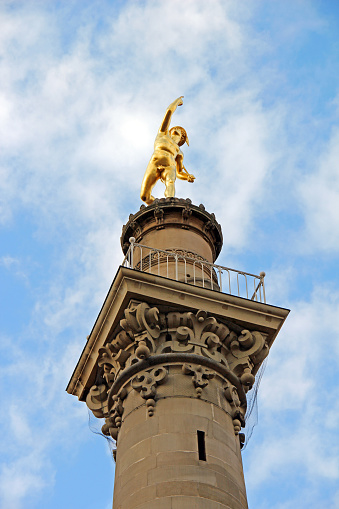 Stuttgart, Germany, 2011 - Famous landmark: golden Hermes statue on a column near Schlossplatz against a blue sky