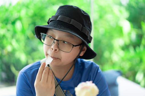 boy with hat eat ice cream cone by spoon