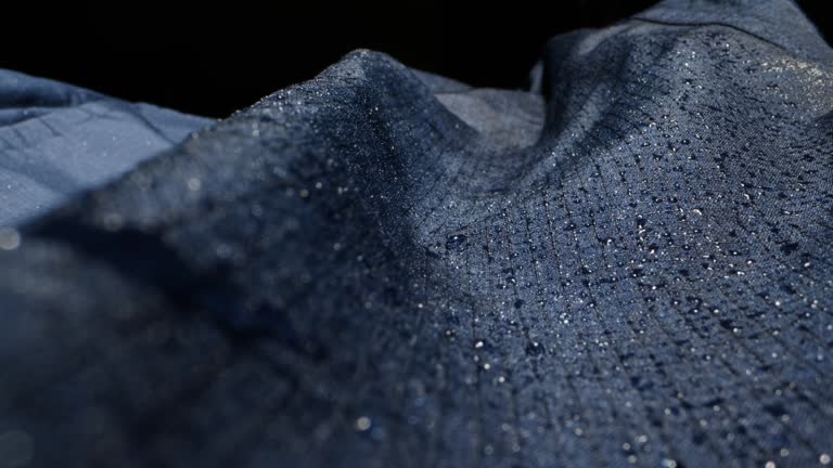 Waterproof clothing for tourism. Blue cloth texture with water drop close-up macro. Repellent waterproof breathable fabrics. Innovation waterproofing material test