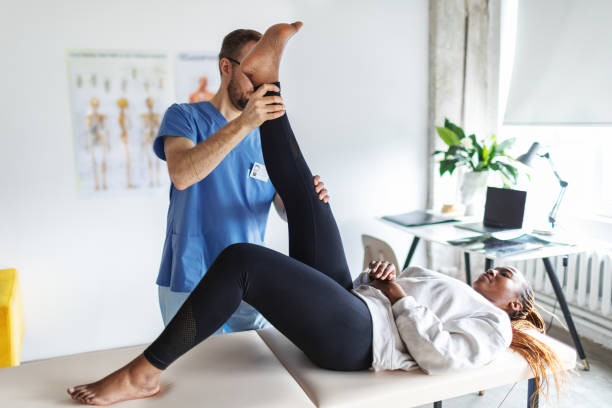 Physical therapist helping young black woman with her legs Physical therapist helping young black woman with her legs chiropractor stock pictures, royalty-free photos & images
