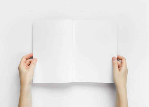 istock Hands holding an open magazine with empty white pages top view 2150156552