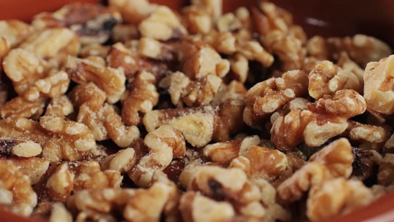 Walnuts without shell close-up macro. Man hand take a piece of walnut. Peeled nuts. Healthy snacks. Product rich in minerals and vitamins.