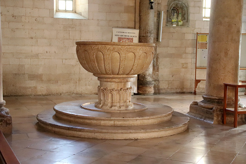 Bitonto, Metropolitan city of Bari, Italy - 25 april 2024: Baptismal font - The cathedral, dedicated to San Valentino and Santa Maria Assunta, is the greatest expression of Apulian Romanesque. Built in the center of the city between the 11th and 12th centuries on the model of the basilica of San Nicola di Bari.