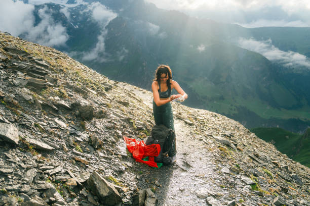 Cheerful woman squeezing wet clothes while hiking in Swiss Alps under the rain