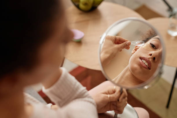 istock Girl Applying Face Mask with Focus on Mirror Reflection 2150167703
