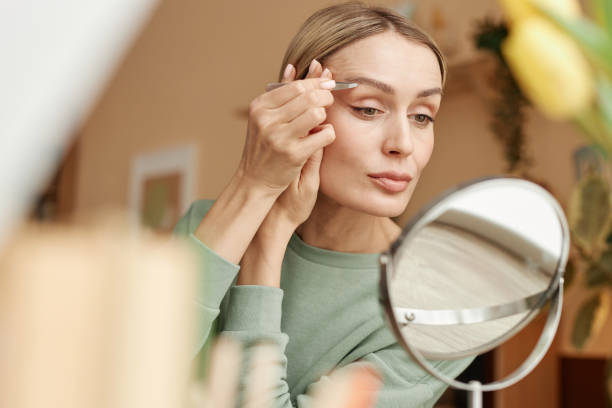Woman Plucking Eyebrows with Tweezers at Home