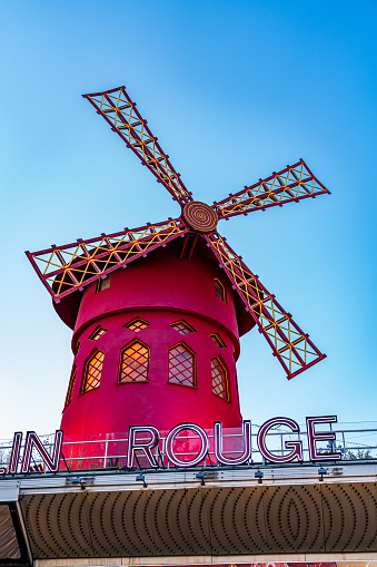 Paris, France. July 6, 2023. Red colored construction of the windmill of the mythical and famous cabaret venue Moulin Rouge located on the boulevard Clichy in the Montmartre district of Paris.
