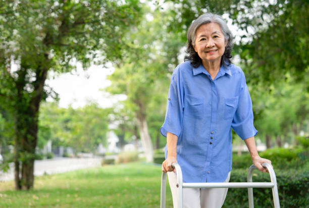 smiling senior woman walking with walker in park