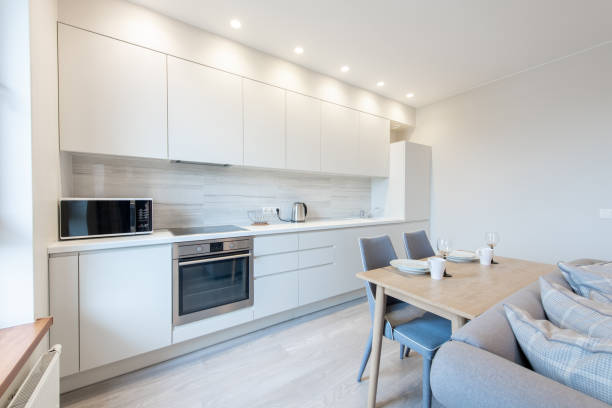 istock Classic White Kitchen Interior and Dinning Table. Oven, Kettle, Microwave and Glass. Plates on the Table. Minimalistic Interior Design 2150170575