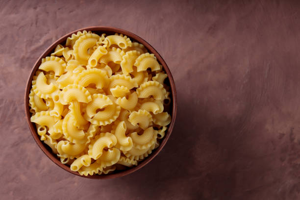 istock Dry Uncooked Creste di Gallo Pasta in Clay Bowl on Brown Background, Copy Space 2150173941