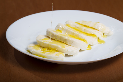 Mozzarella cheese slices on white plate, drizzled with extra virgin olive oil. Healthy food concept.