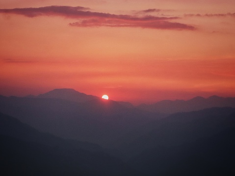 a sun setting behind the mountains in the uttarakhand state in himalayan range