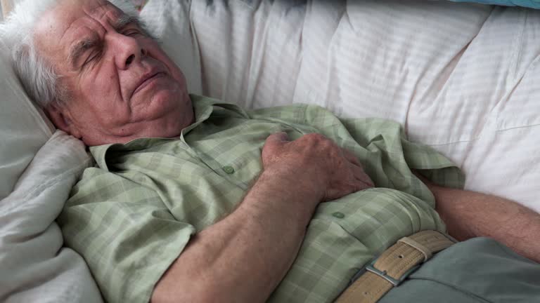 Elderly Old Man Feels Bad Lying On Bed And Holding His Heart