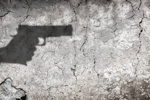 istock The shadow of the hand holding a gun reflected on the wall 2150180289