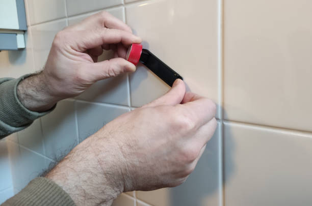 A man collects samples of bacteria from the surface of a wall in a public shower.