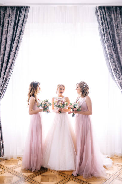 istock Cheerful bride with a bouquet in her hands stands next to her gi 2150187257