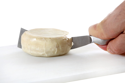 chef cutting cheese with specific knife on white background