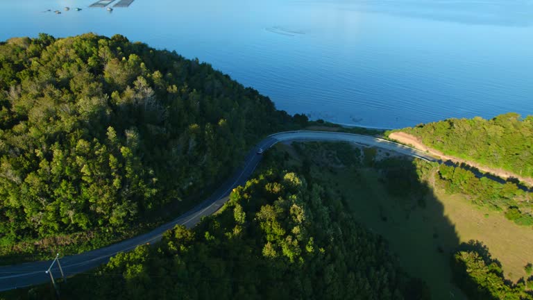 Aerial view tracking a car through the narrow channel on Lemuy Island towards Detif in Chiloe. dangerous road. Patagonia