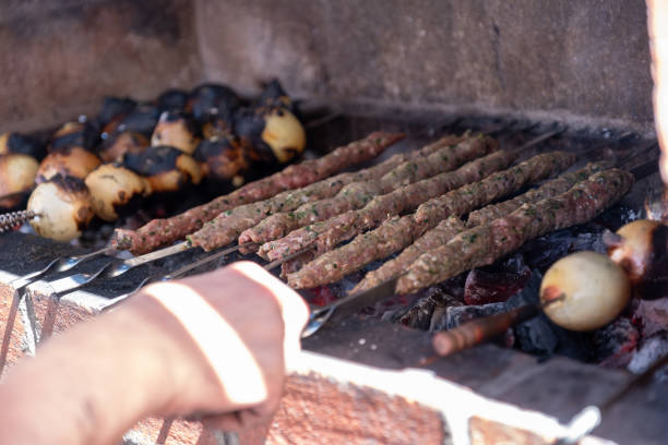 hands preparing barbeque on stone stove during his party time
