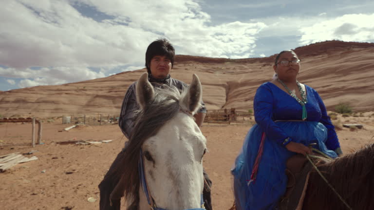Young Navajo Couple in Their Twenties Riding Horses Bareback on Family Ranch in Monument Valley Tribal Park with Beautiful Rock Formations in the Background