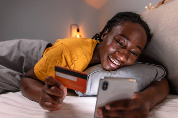 istock Young woman lying in bed and doing online shopping 2150195307
