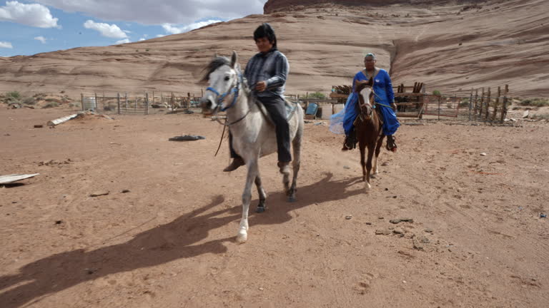 Young Navajo Couple in Their Twenties Riding Horses Bareback on Family Ranch in Monument Valley Tribal Park with Beautiful Rock Formations in the Background