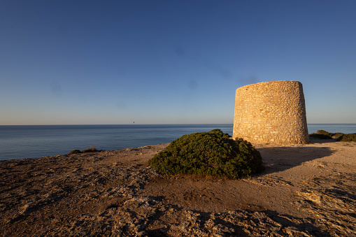 A fortified tower on the Portuguese coast on a rock with raw vegetation