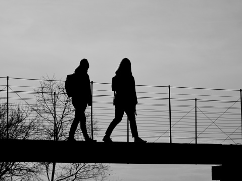 An artistic black and white silhouette of two people walking on the bridge at the Ljubljana Castle (Ljubljanski Grad) in Ljubljana, Slovenia