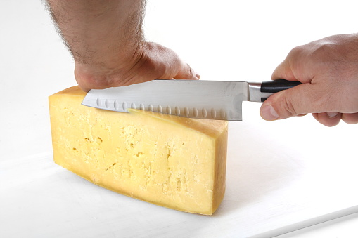 chef cutting cheese with specific knife on white background